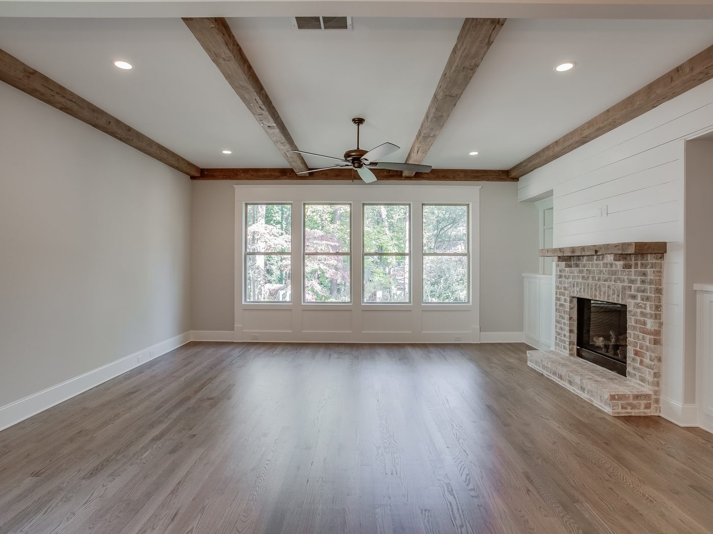 A living room hardwood floor finished wall to wall, the grain reading evenly across the room in daylight